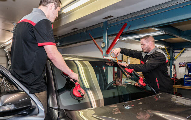 two mechanics repairing the front glass of the car