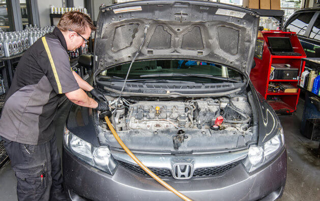 Open car hood being repaired by mechanic