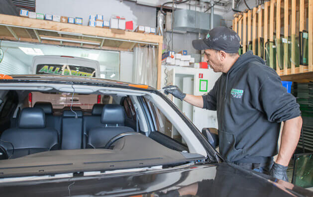 A man cleaning the edges of a car without a windshield.
