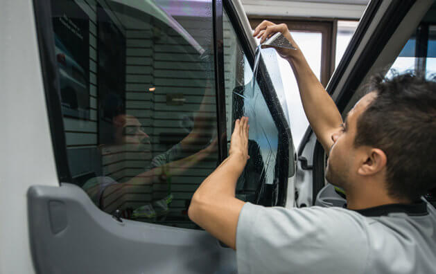 A man installing a Window film in a window to darken it.
