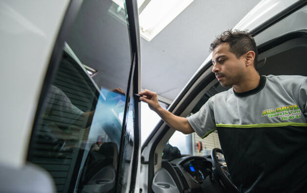A man givingthe finishing touches on a tinted window.