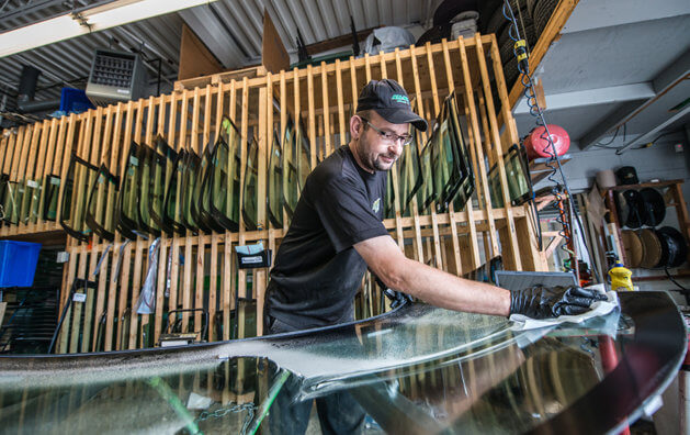 A man cleaning a new windshield before placing it in the car.