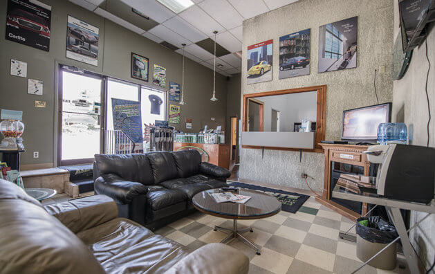 Waiting area with two large leather armchairs placed perpedicularly, and a small round glass table in the middle.