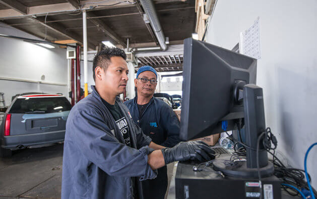 two mechanics watching a screen