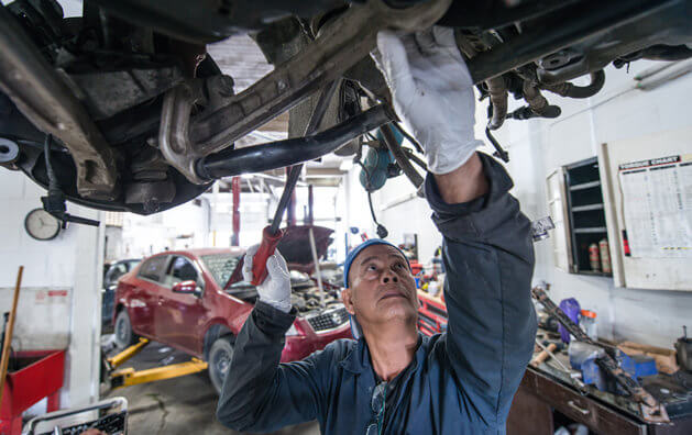 automotive mechanic checking the bottom of the car