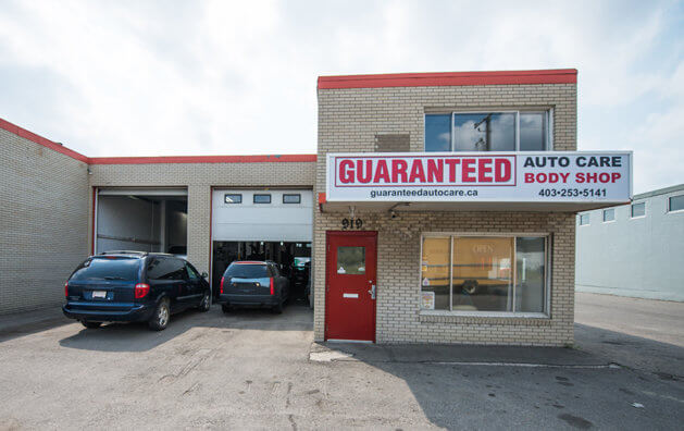 front of the company with red door, entrance to the garage and two black cars entering