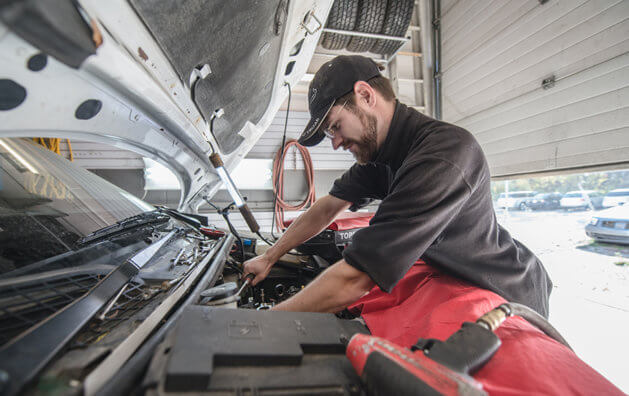 Man using a spanner to work in the engine of a car.